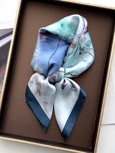 Détail d'un foulard en soie aux motifs floraux abstraits posé sur un plateau d'exposition