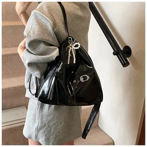 Detail of a black glossy backpack with silver zippers and a pearl bow charm accessory