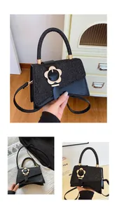 Détail d'un sac à main noir avec boucle fleur dorée et textures contrastées élégantes