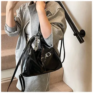 Close-up of black glossy patent leather shoulder bag with decorative pearl pendant and silver hardware