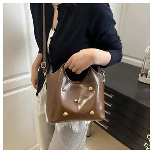 Brown glossy tote bag featuring gold dog and bone charms shown on model for daily commute