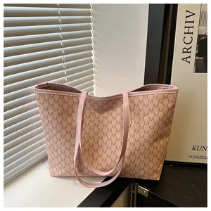 Detailed view of pink tote bag featuring a repeating M monogram pattern and slim straps