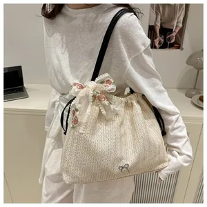 Détail du sac en paille avec broderie de ruban de dentelle et badge en métal argenté