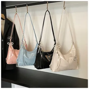 Detailed row of glossy patent leather shoulder bags featuring pearl bow charms in four colors