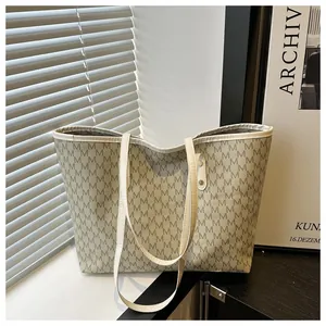 Detailed close-up of large tote bag featuring repeated M letter prints and white top handles
