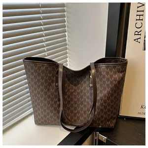 Close-up of retro monogram pattern and premium leather straps on a brown tote bag