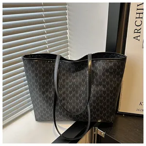 Macro shot of large tote bag with repetitive M letter print and slim shoulder straps