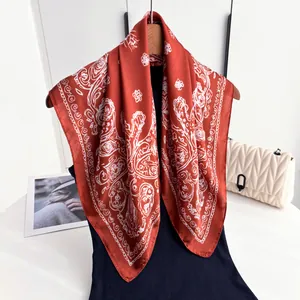 Brick red faux silk square scarf with white floral patterns styled on elegant outfit