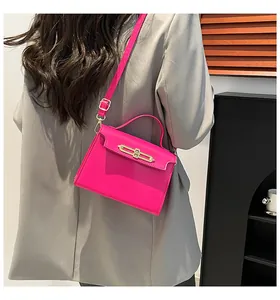 Bolso fucsia con hebilla dorada mostrado por una modelo con un traje grisáceo