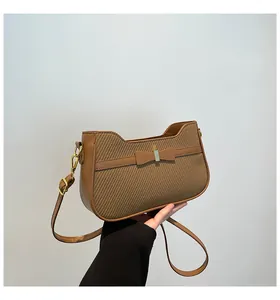 Dettaglio della trama intrecciata e fiocco in pelle su borsa marrone con fibbie dorate