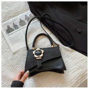Détail du sac à main noir avec boucle fleur dorée présenté dans un décor de mode chic