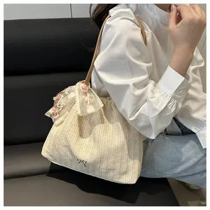 Détail du sac cabas en paille avec broderie de fleurs en dentelle et nœud en métal