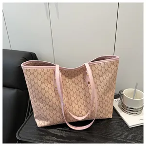 Detailed view of beige tote bag with M-letter print and pink trim on wooden table