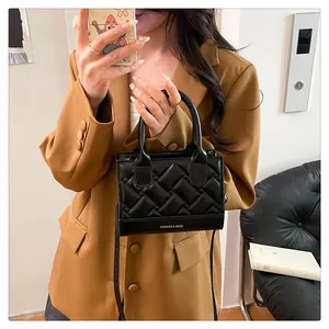 Detail van zwarte gewatteerde lederen handtas met logo gedragen door model in blazer