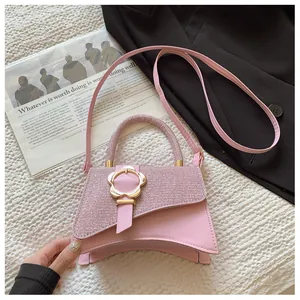 Détail d'un sac à main rose pailleté avec une boucle en métal en forme de fleur dorée