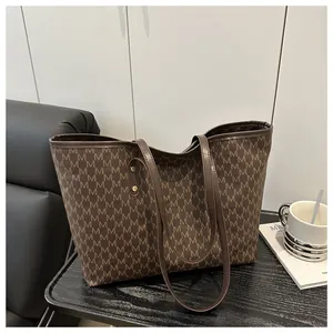 Close-up of vintage brown tote bag with M-letter pattern and golden rivet details