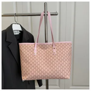 Detail of pink vintage tote bag with brown M pattern and gold studs on handles
