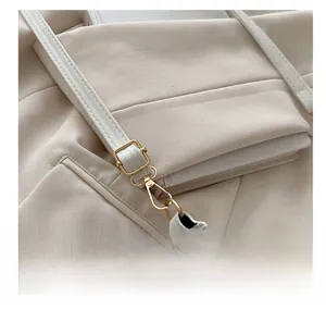 Close-up of adjustable strap with gold metal buckle on white leather crescent bag
