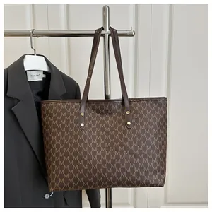 Detail of vintage M-print brown tote bag displayed on a sleek black business blazer