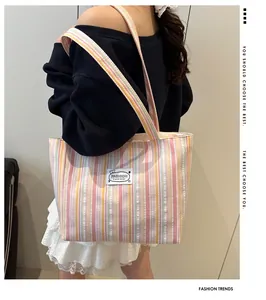 Sac fourre-tout en toile à rayures avec motifs rose, jaune et bleu portés à l'épaule