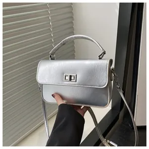 Close-up of silver rectangle metal turn-lock and fine embossed texture on handbag
