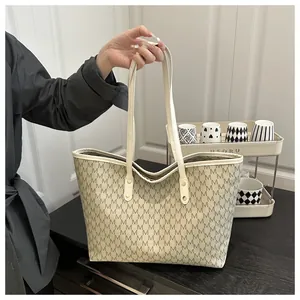 Macro detail of large tote bag with dark grey monogram print and slim shoulder straps