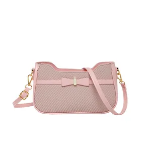 Borsa a spalla rosa con trama intrecciata, fiocco decorativo e tracolla dorata