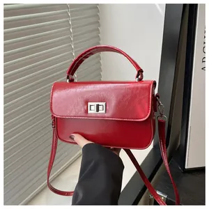 Detail of red glossy patent leather square handbag featuring silver square metal twist lock