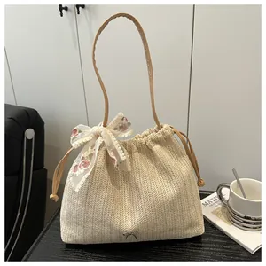 Gros plan d'un sac cabas en paille avec nœud en dentelle et bandoulière en similicuir