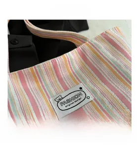 Détail du sac cabas en toile à rayures colorées montrant l'écusson de design original