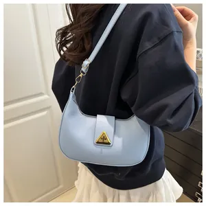 Close-up of light blue crescent underarm bag with gold triangle buckle on a model