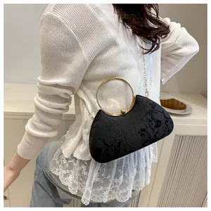 Close-up of crescent evening bag with floral texture and large gold circular handle