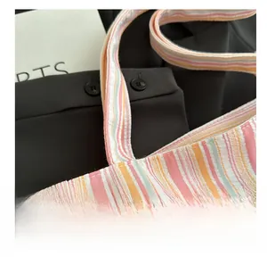 Détail des coutures robustes sur les anses du sac cabas en toile rayée et texture