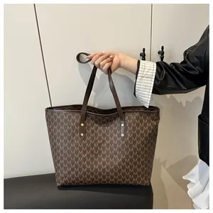 Detail shot of vintage brown tote bag featuring M-pattern print and gold rivet hardware