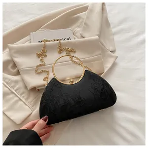 Detail of black evening clutch with floral embroidery and gold round metal handle