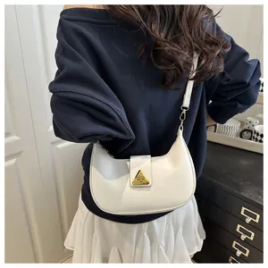 Detail of white leather crescent bag featuring a gold triangle buckle on shoulder strap