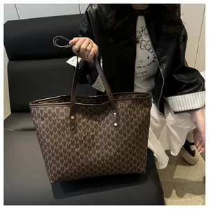 Detail view of large tote bag with vintage brown monogram print and leather handles