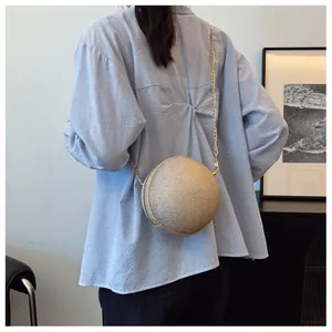Chic gold spherical chain crossbody bag styled on a model in a modern interior setting