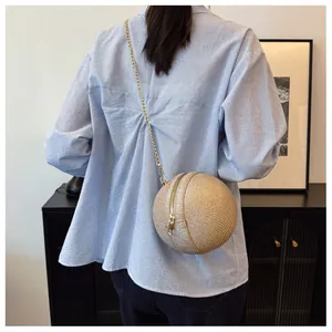 Detail of a champagne gold spherical crossbody bag with woven texture and gold chain