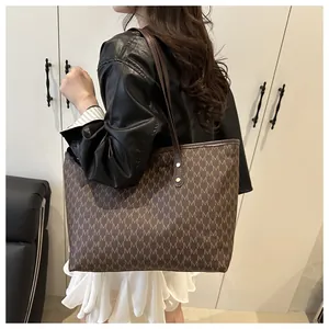 Detail showing the monogram pattern and leather handle of this brown tote bag