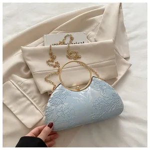 Detail of light blue evening bag with floral embroidery and gold metal handle