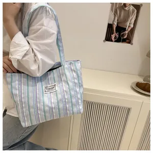 Détail d'un cabas en toile rayée montrant le tissu texturé et l'étiquette de mode