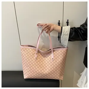 Close-up of spacious tote bag with monogram print and golden rivet reinforced handles
