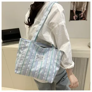 Détail du sac fourre-tout en toile à rayures avec logo et coutures renforcées pour femme