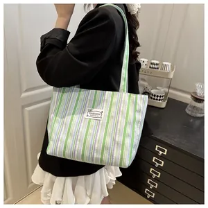 Détail du patch logo tissé sur un sac cabas en toile à rayures vertes et violettes