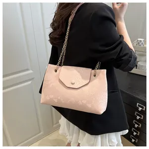 Détail du sac à main rose gaufré serpent avec chaîne dorée porté par un mannequin