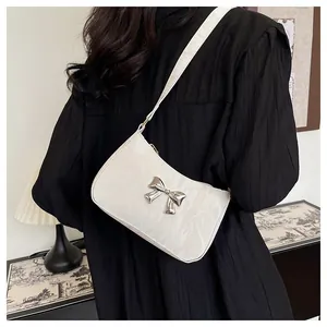 Gros plan sur le sac blanc texturé avec un nœud décoratif en métal argenté brillant