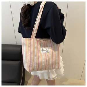 Détail du sac cabas en toile rayé rose et jaune avec un patch d'ours mode pour étudiante