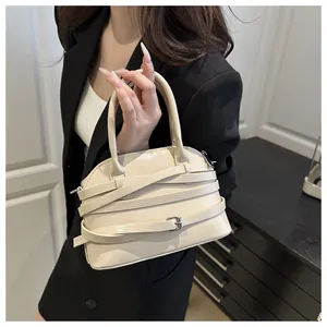Vista dettagliata della borsa beige crema con cinturini avvolgenti su blazer nero