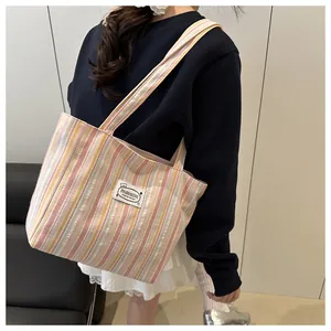 Détail du sac cabas en toile à rayures montrant la texture du tissu et la bandoulière large